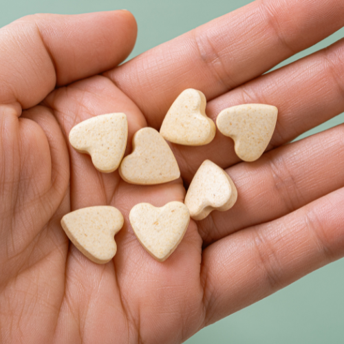 Heart shaped pet vitamins in the palm of a hand.